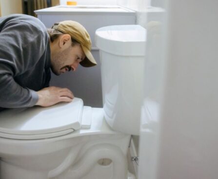 Person installing new toilet seat hinges with tools on bathroom floor