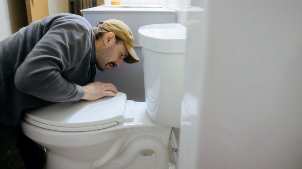 Person installing new toilet seat hinges with tools on bathroom floor
