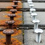 Corroded roofing fasteners showing rust damage compared to new stainless steel fasteners on roof deck