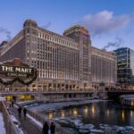 Exterior view of THE MART Chicago Art Deco building along the Chicago River during the winter holiday season with hotel towers visible nearby