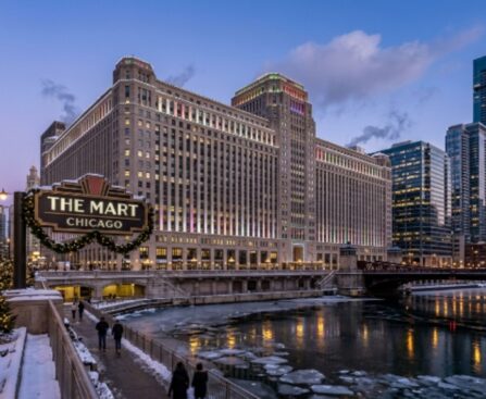 Exterior view of THE MART Chicago Art Deco building along the Chicago River during the winter holiday season with hotel towers visible nearby
