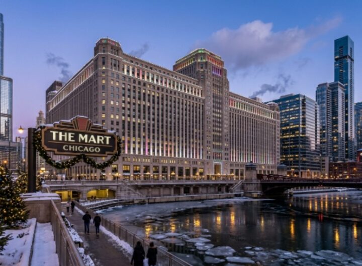 Exterior view of THE MART Chicago Art Deco building along the Chicago River during the winter holiday season with hotel towers visible nearby
